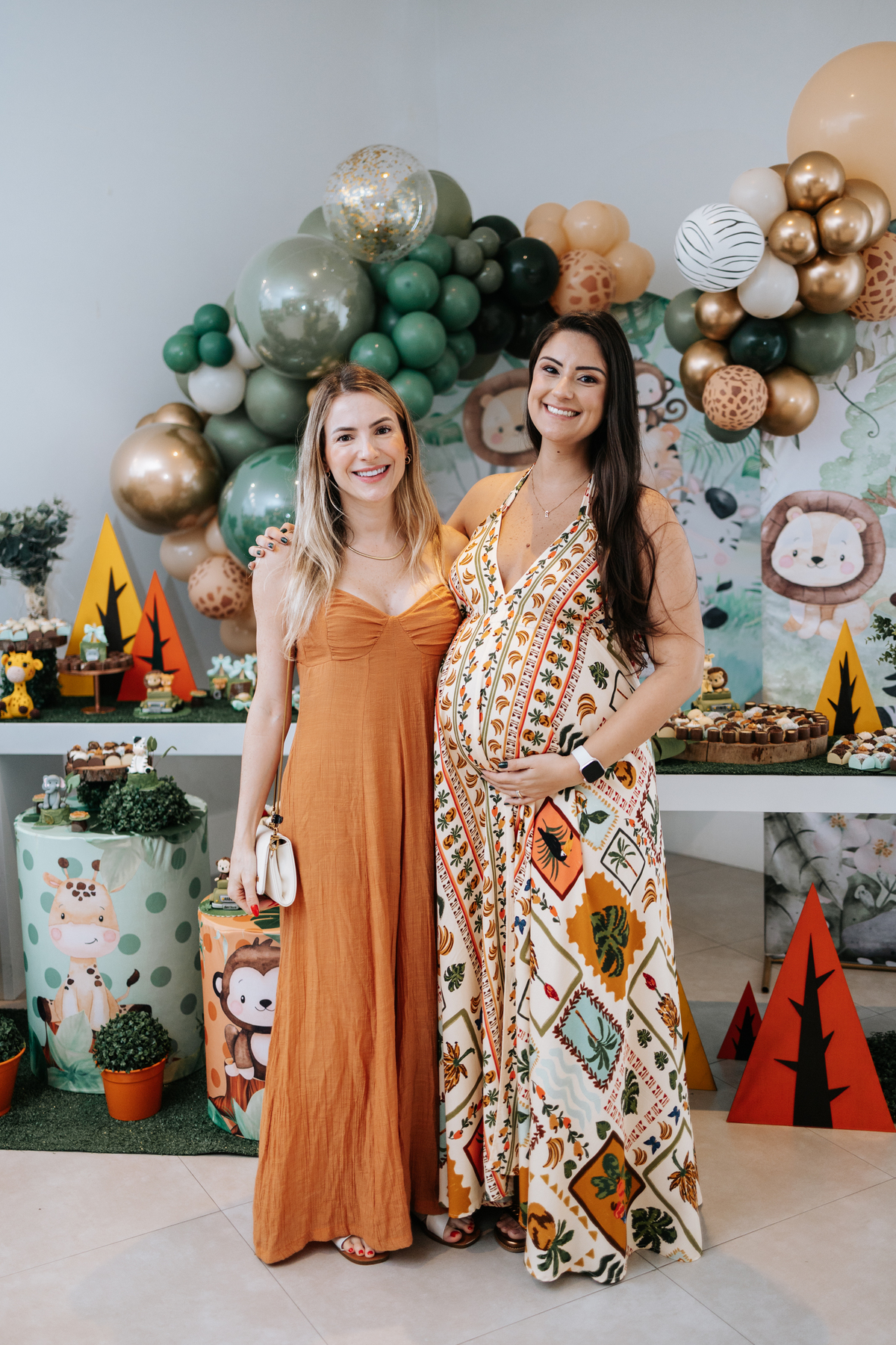 Foto da gestante posando com amiga em frente à decoração Safari.