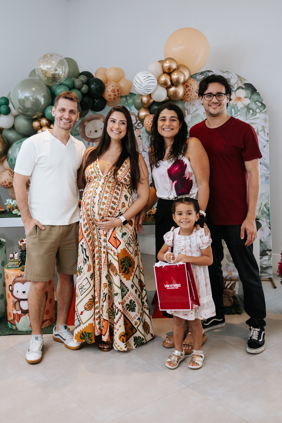 Foto oficial do casal com convidados e uma criança na mesa do bolo.