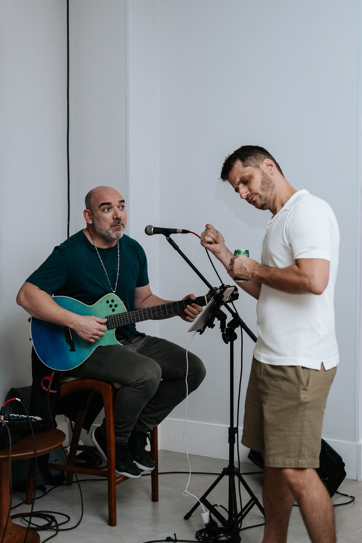 Foto do músico apresentando show ao vivo com violão no chá e pai se divertindo ao lado. 