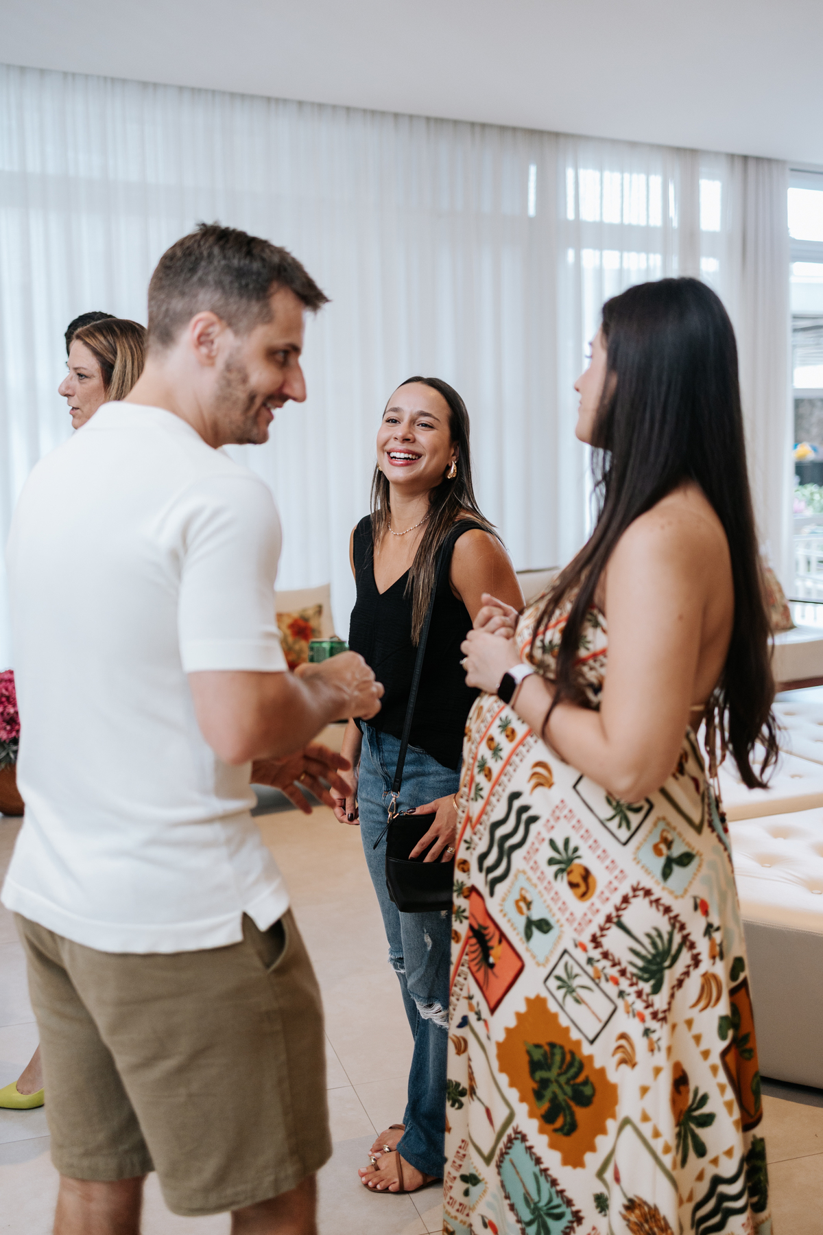 Foto do casal interagindo e rindo com os convidados no salão.