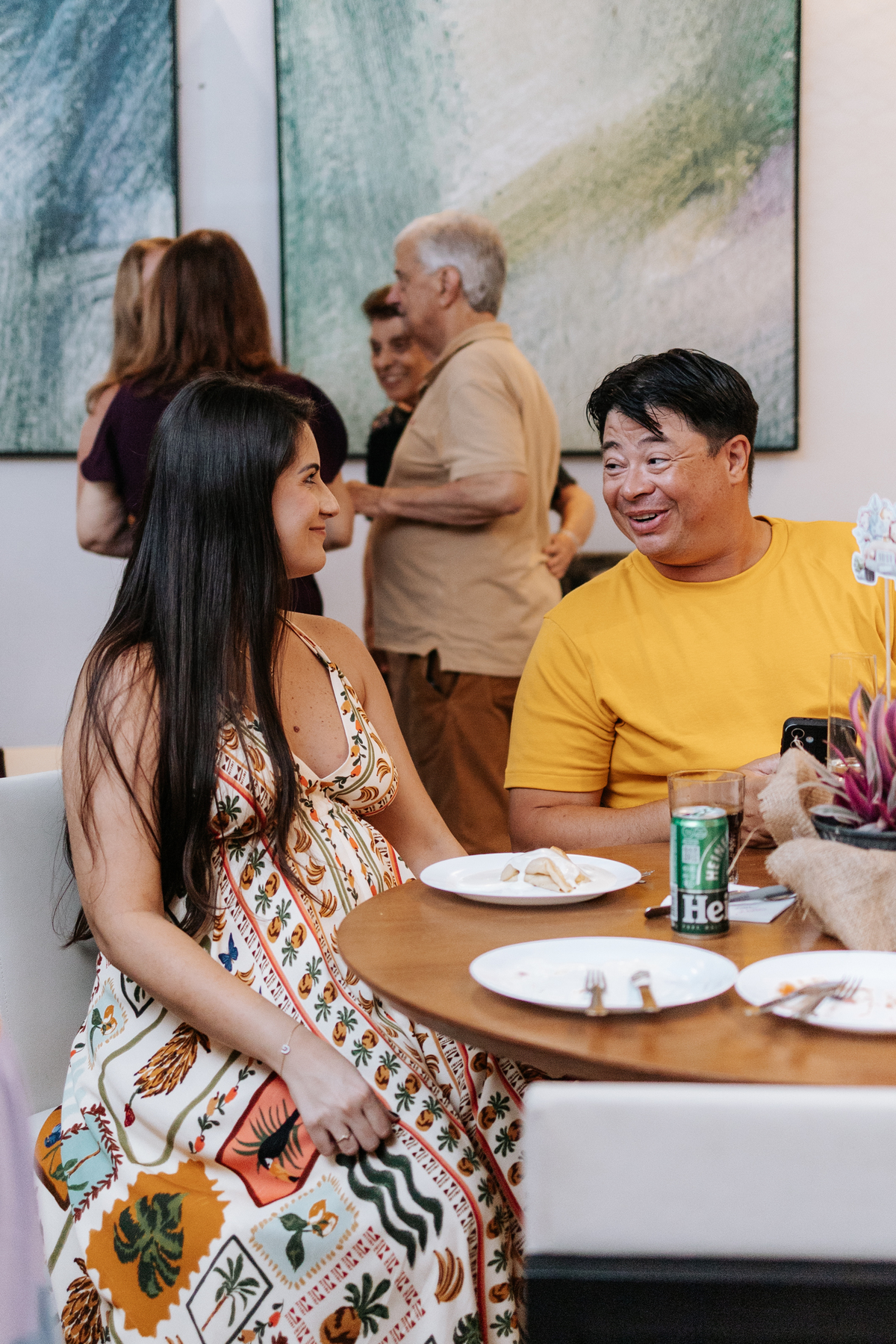 Foto da gestante sentada conversando com convidados na mesa.