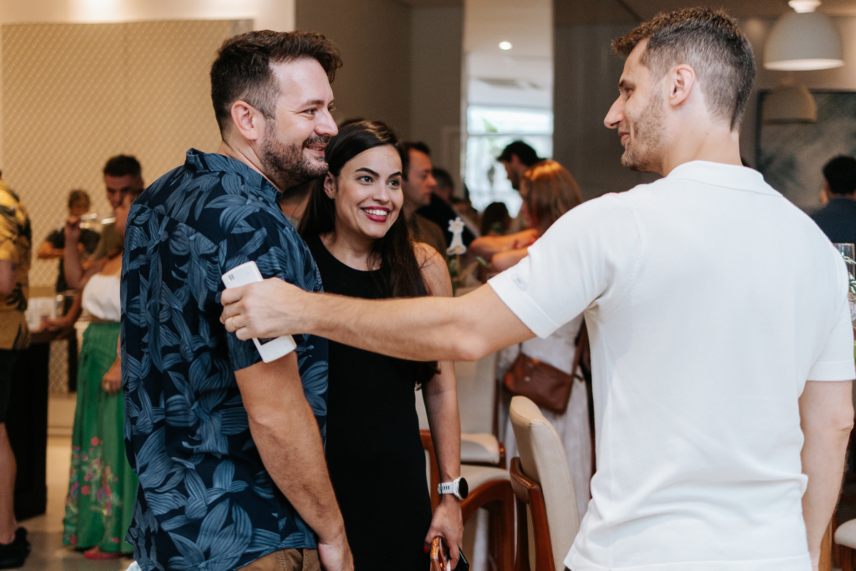 Foto do futuro papai interagindo com amigos no salão de festas.