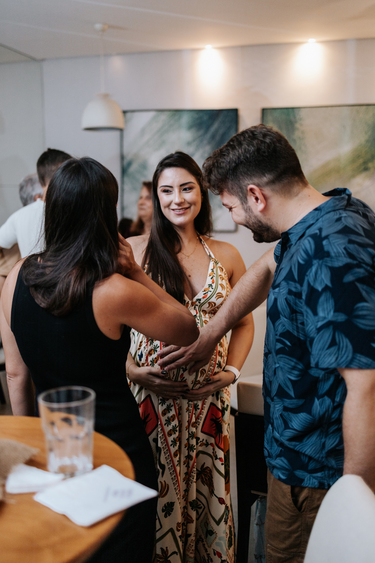 Foto de amigos reunidos fazendo carinho na barriga da gestante.