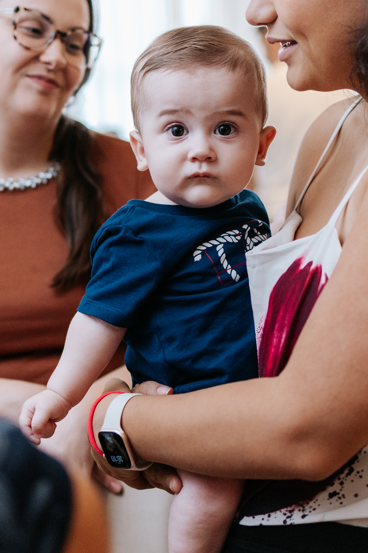 Foto em detalhe de uma criança no colo durante a celebração.