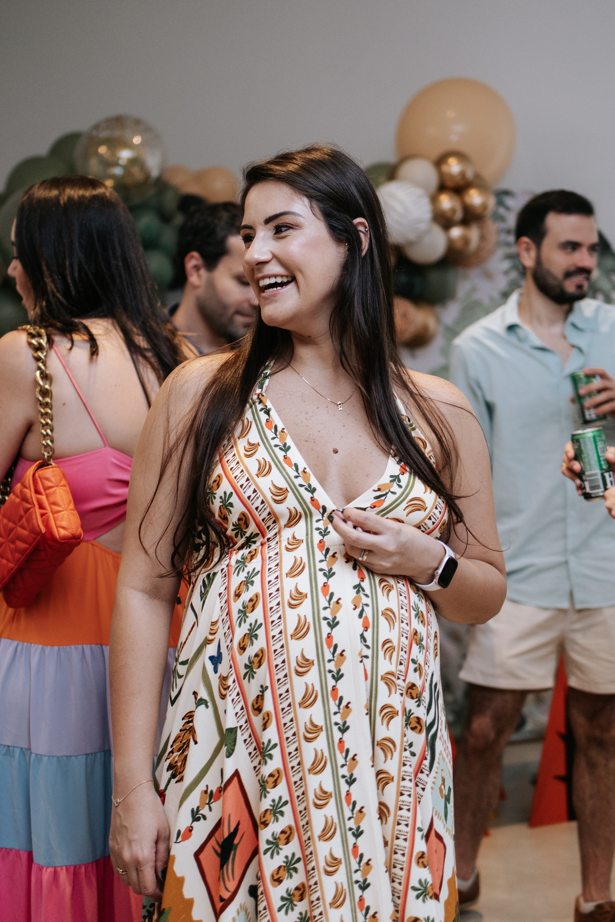 Foto espontânea da gestante sorrindo em meio aos convidados no salão.