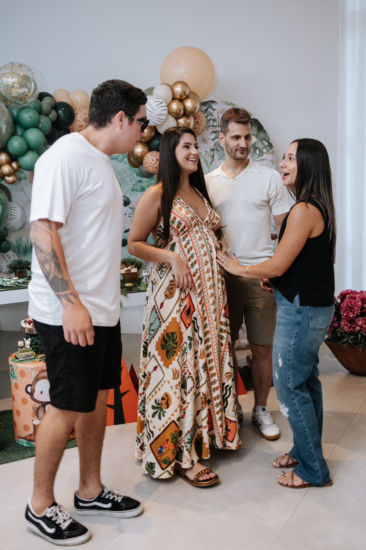 Foto do casal posando com um grupo de amigos próximos à mesa do bolo.