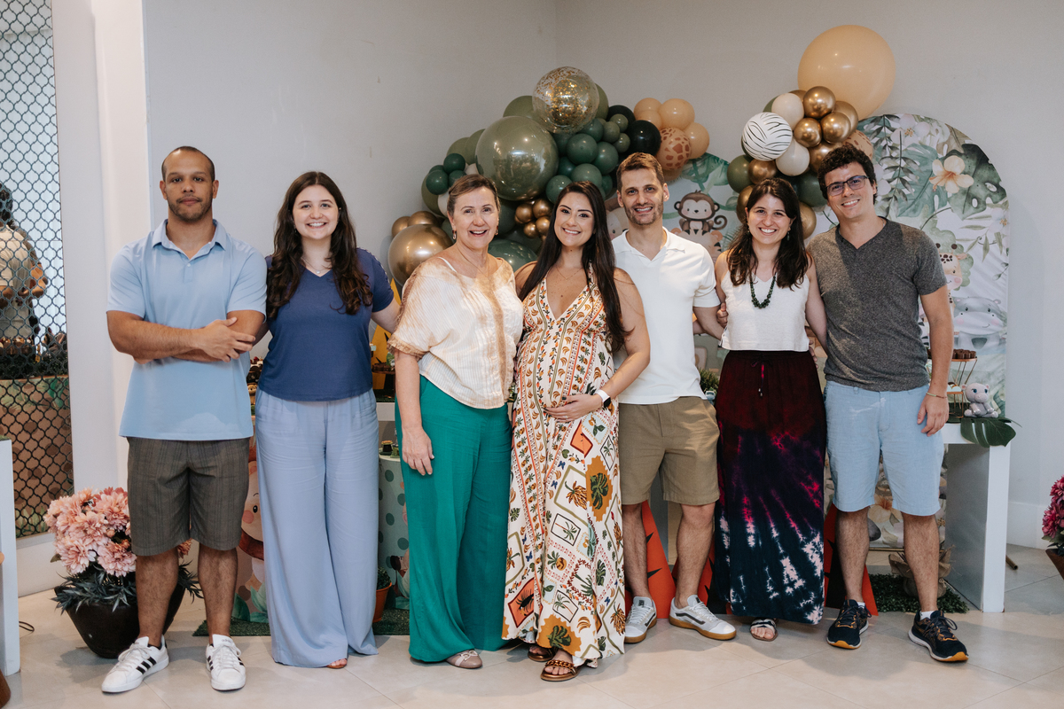 Foto em grupo com amigos e familiares sorridentes no painel de balões.