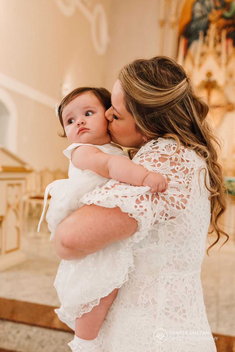 Família reunida diante do altar após o batizado, em um momento de gratidão e alegria.