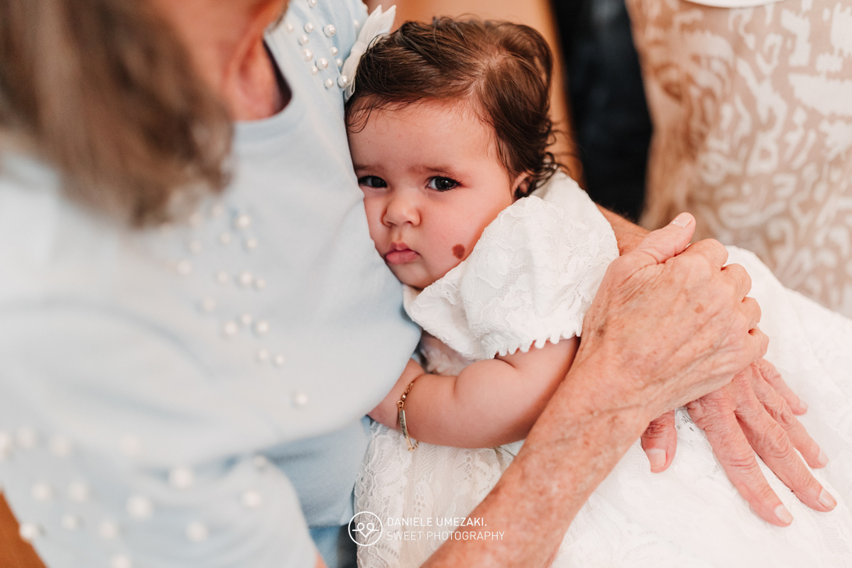 Pais com a bebê Alana no colo durante o batizado na Igreja do Socorro – registro de batizado com fotógrafa especializada em família