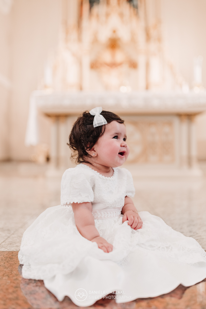 Pais com a bebê Alana no colo durante o batizado na Igreja do Socorro – registro de batizado com fotógrafa especializada em família