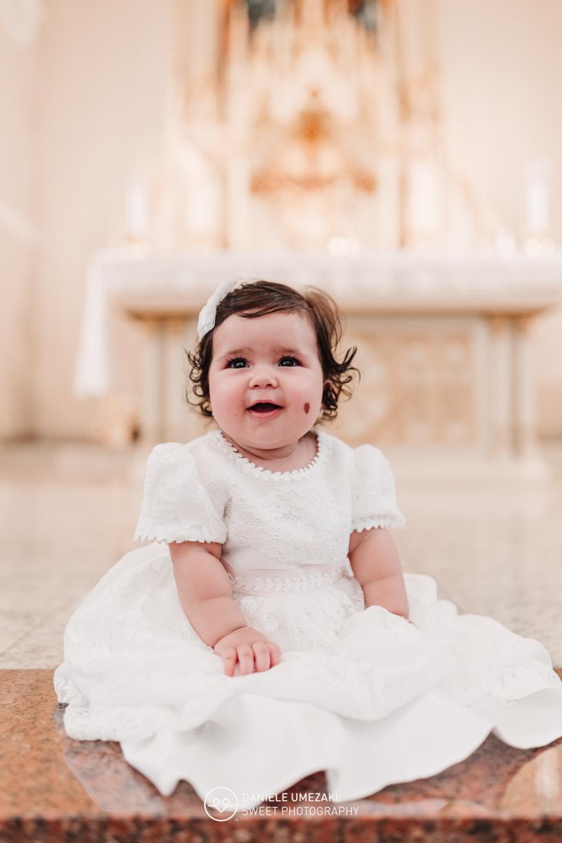 Pais com a bebê Alana no colo durante o batizado na Igreja do Socorro – registro de batizado com fotógrafa especializada em família