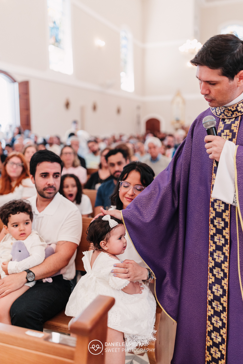 Pais com a bebê Alana no colo durante o batizado na Igreja do Socorro – registro de batizado com fotógrafa especializada em família