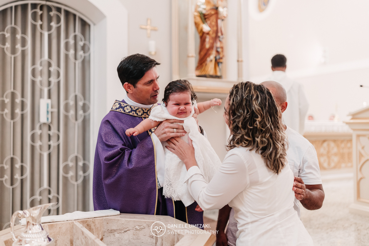 Pais com a bebê Alana no colo durante o batizado na Igreja do Socorro – registro de batizado com fotógrafa especializada em família