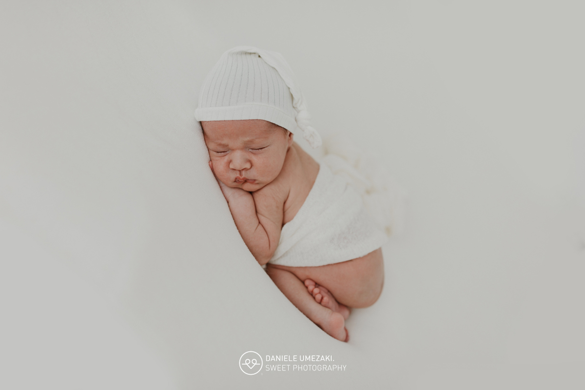 Fotografia de ensaio newborn em Mogi das Cruzes com o Benício, aos 17 dias de vida. Um registro feito com carinho, luz natural e cenário neutro, no estúdio da fotógrafa Dani Umezaki, pensado para o conforto e segurança do bebê e da família.