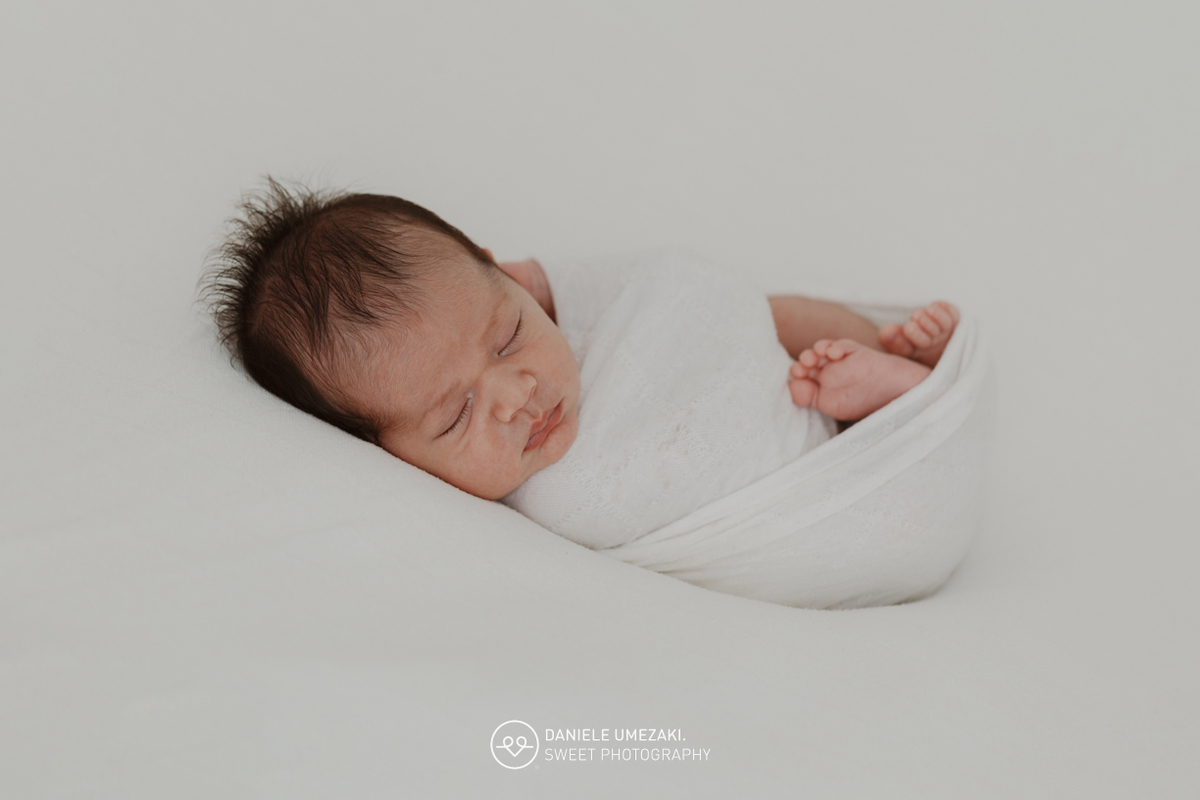 Fotografia de ensaio newborn em Mogi das Cruzes com o Benício, aos 17 dias de vida. Um registro feito com carinho, luz natural e cenário neutro, no estúdio da fotógrafa Dani Umezaki, pensado para o conforto e segurança do bebê e da família.