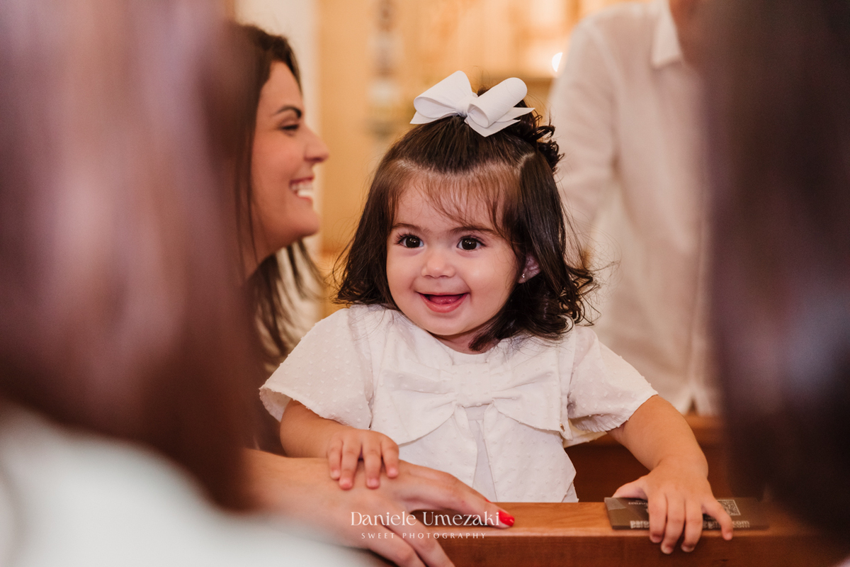 Fotografia de batizado em Mogi das Cruzes realizada por Dani Umezaki. Cerimônia da Malu e do Bernardo na Igreja do Socorro, com registros afetivos e cheios de significado. Família acompanhada desde o chá revelação e aniversários.