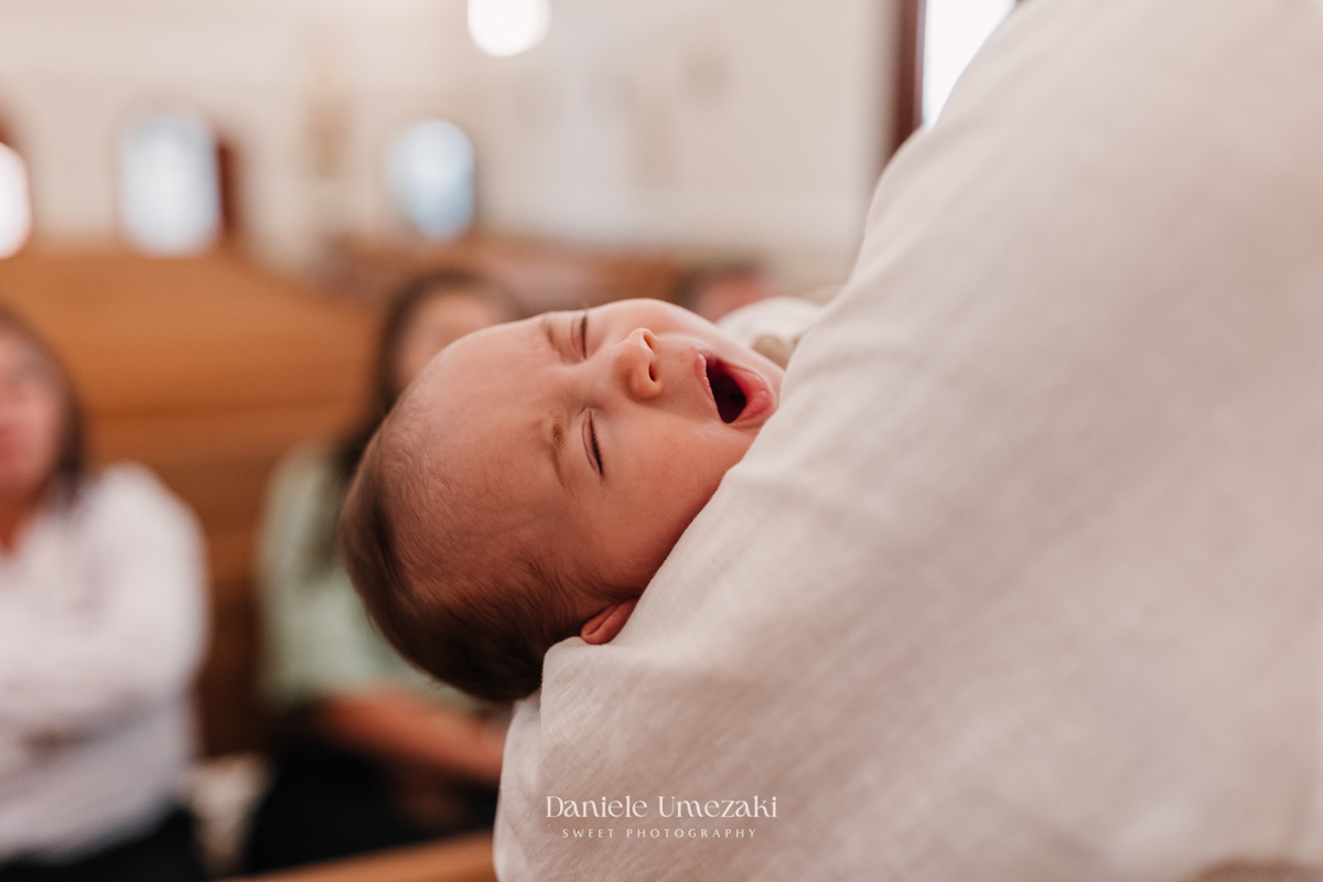 Fotografia de batizado em Mogi das Cruzes realizada por Dani Umezaki. Cerimônia da Malu e do Bernardo na Igreja do Socorro, com registros afetivos e cheios de significado. Família acompanhada desde o chá revelação e aniversários.