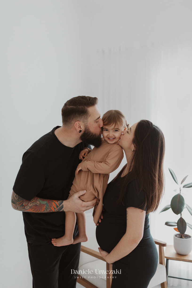 Ensaio gestante leve e atemporal realizado em estúdio na Vila Oliveira, Mogi das Cruzes. Camila, Adriano e a filha Laura celebram a doce espera do Pedro em um ensaio cheio de afeto e conexão. ensaio gestante mogi das cruzes, fotografia gestante 