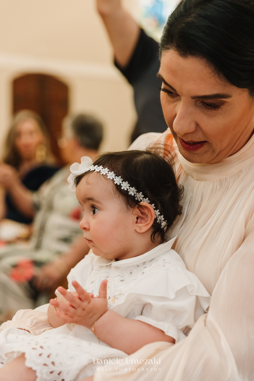 Fotografia de batizado na Igreja do Socorro, em Mogi das Cruzes. Cerimônia conduzida pelo Padre Michel, com almoço em família e decoração da Cerejeira Decora. Registro afetivo por Dani Umezaki
