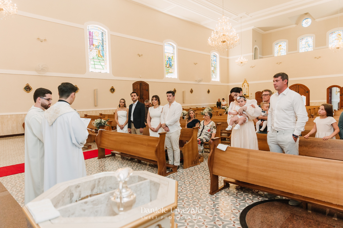Fotografia de batizado na Igreja do Socorro, em Mogi das Cruzes. Cerimônia conduzida pelo Padre Michel, com almoço em família e decoração da Cerejeira Decora. Registro afetivo por Dani Umezaki