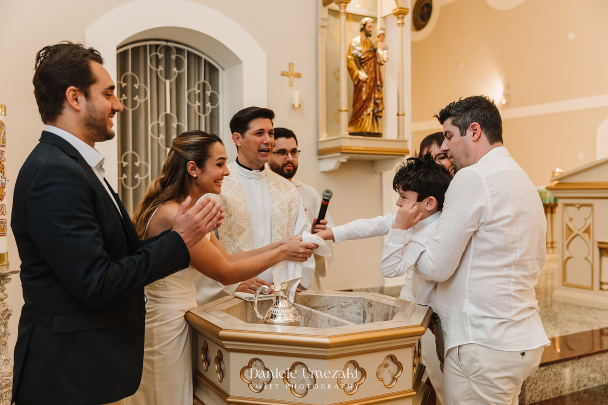 Fotografia de batizado na Igreja do Socorro, em Mogi das Cruzes. Cerimônia conduzida pelo Padre Michel, com almoço em família e decoração da Cerejeira Decora. Registro afetivo por Dani Umezaki