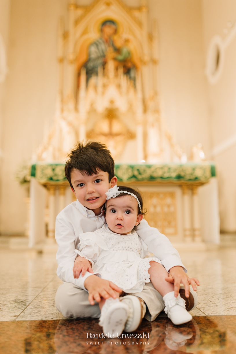 Fotografia de batizado na Igreja do Socorro, em Mogi das Cruzes. Cerimônia conduzida pelo Padre Michel, com almoço em família e decoração da Cerejeira Decora. Registro afetivo por Dani Umezaki