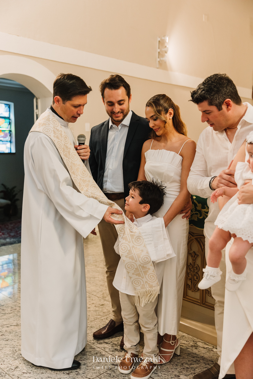 Fotografia de batizado na Igreja do Socorro, em Mogi das Cruzes. Cerimônia conduzida pelo Padre Michel, com almoço em família e decoração da Cerejeira Decora. Registro afetivo por Dani Umezaki