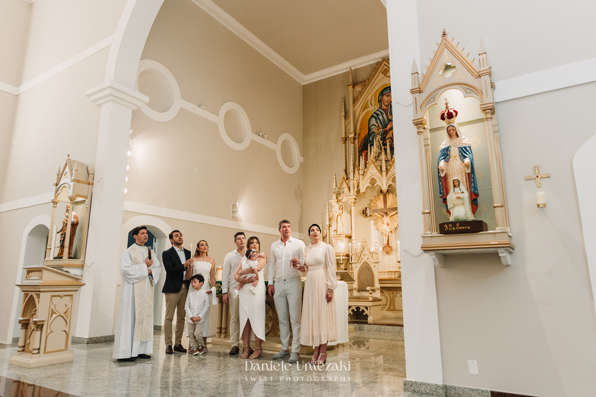 Fotografia de batizado na Igreja do Socorro, em Mogi das Cruzes. Cerimônia conduzida pelo Padre Michel, com almoço em família e decoração da Cerejeira Decora. Registro afetivo por Dani Umezaki