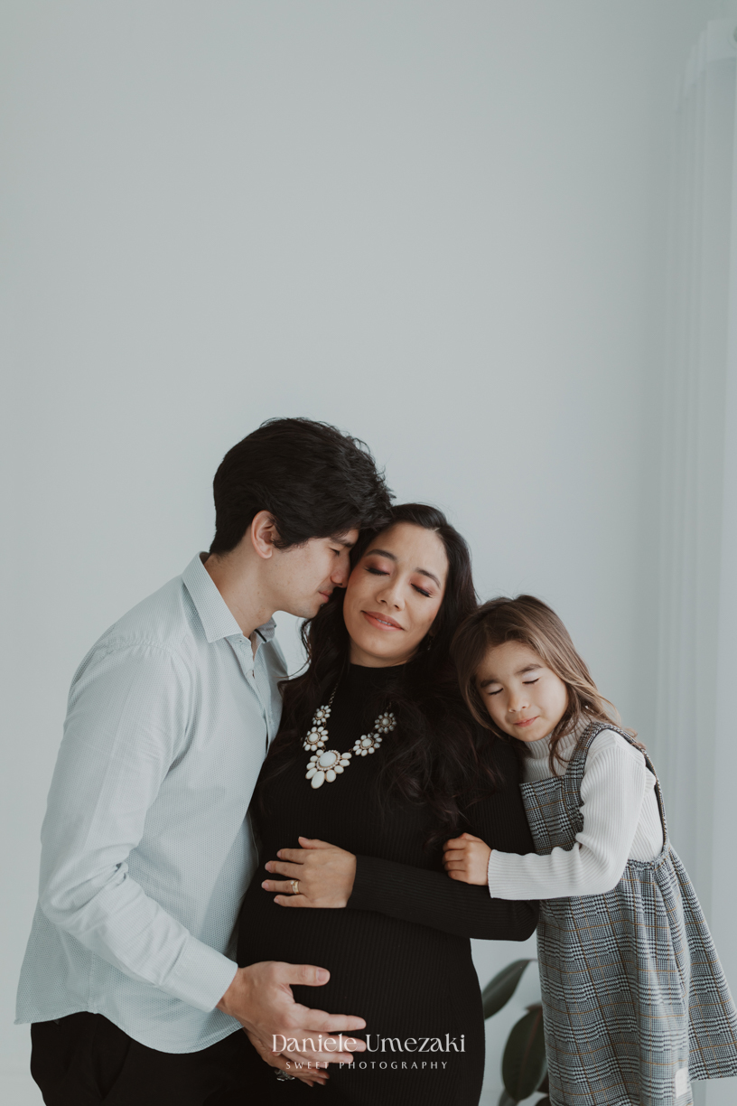 Ensaio gestante da Renata e do Renan em Mogi das Cruzes, com participação da Marina anunciando a chegada da Camila. Fotografia leve e afetiva por Dani Umezaki, especialista em registrar histórias de família com naturalidade e emoção.