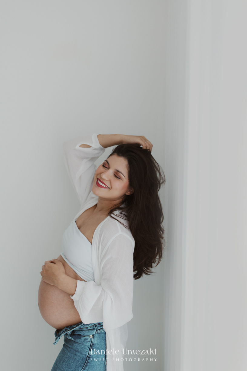 Fotografia de ensaio gestante em Mogi das Cruzes, com a gestante Amanda em pose natural e elegante, em estúdio clean, com luz suave e clima de tranquilidade.