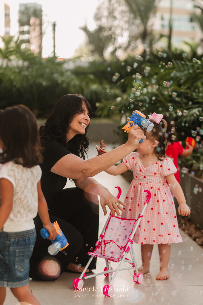 Aurora se divertindo com bolinhas de sabão durante seu aniversário de 2 anos. Fotografia de aniversário infantil em Mogi das Cruzes, com registros espontâneos e afetivos por Dani Umezaki