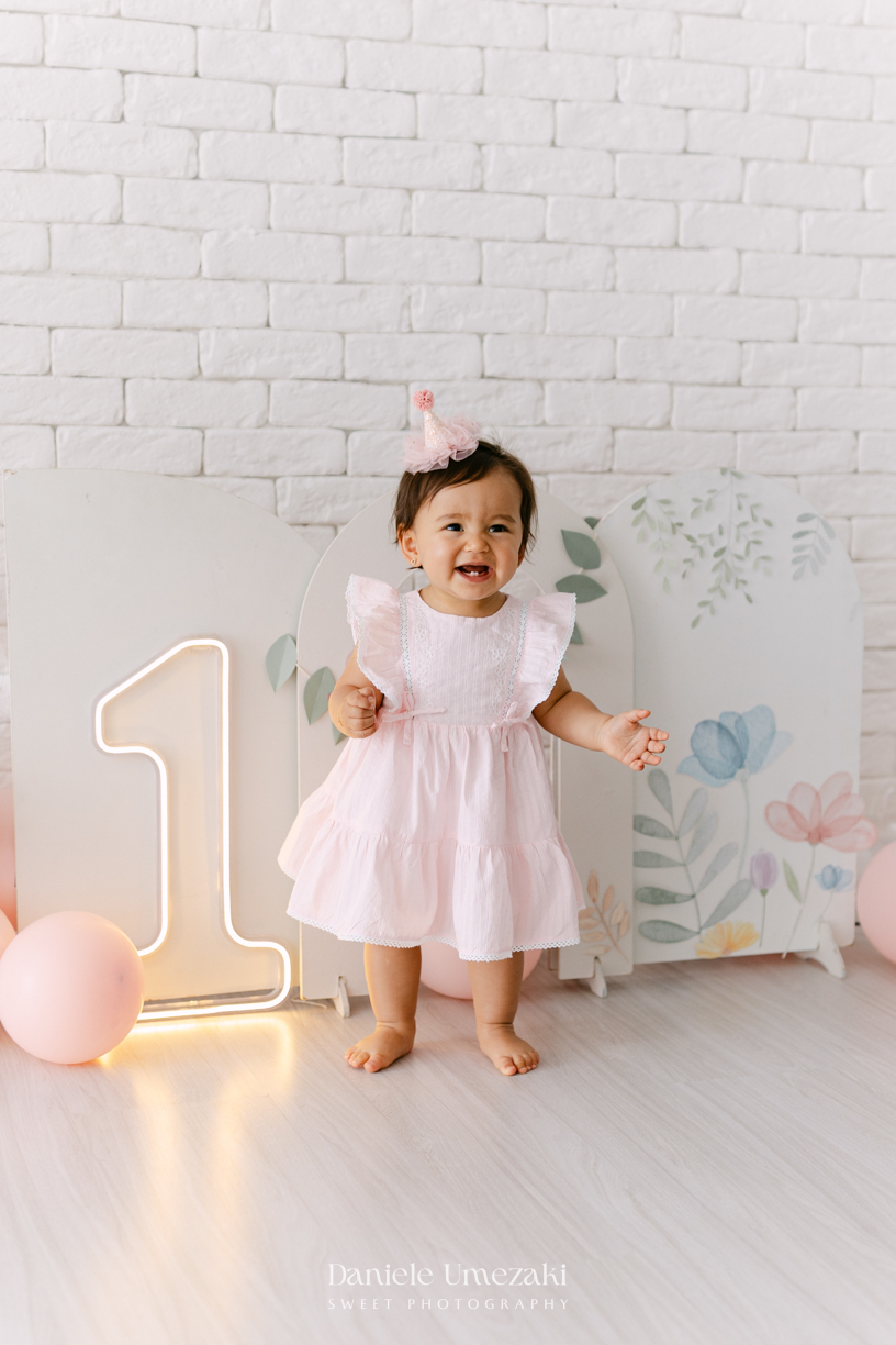 Smash the Cake da Luiza realizado em estúdio em Mogi das Cruzes, com bolo da Ume Doces. Ensaio fotográfico infantil registrando os primeiros momentos do aniversário de 1 ano com leveza, diversão e afeto.