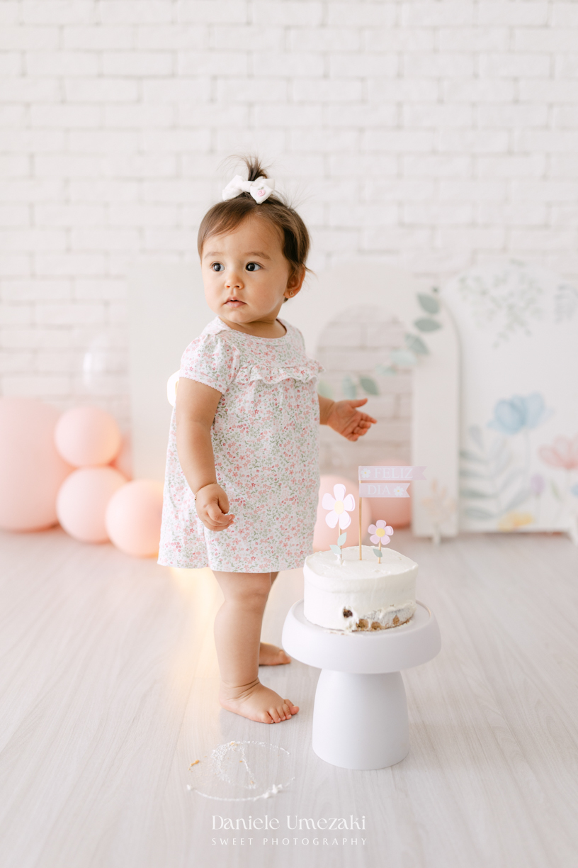 Smash the Cake da Luiza realizado em estúdio em Mogi das Cruzes, com bolo da Ume Doces. Ensaio fotográfico infantil registrando os primeiros momentos do aniversário de 1 ano com leveza, diversão e afeto.