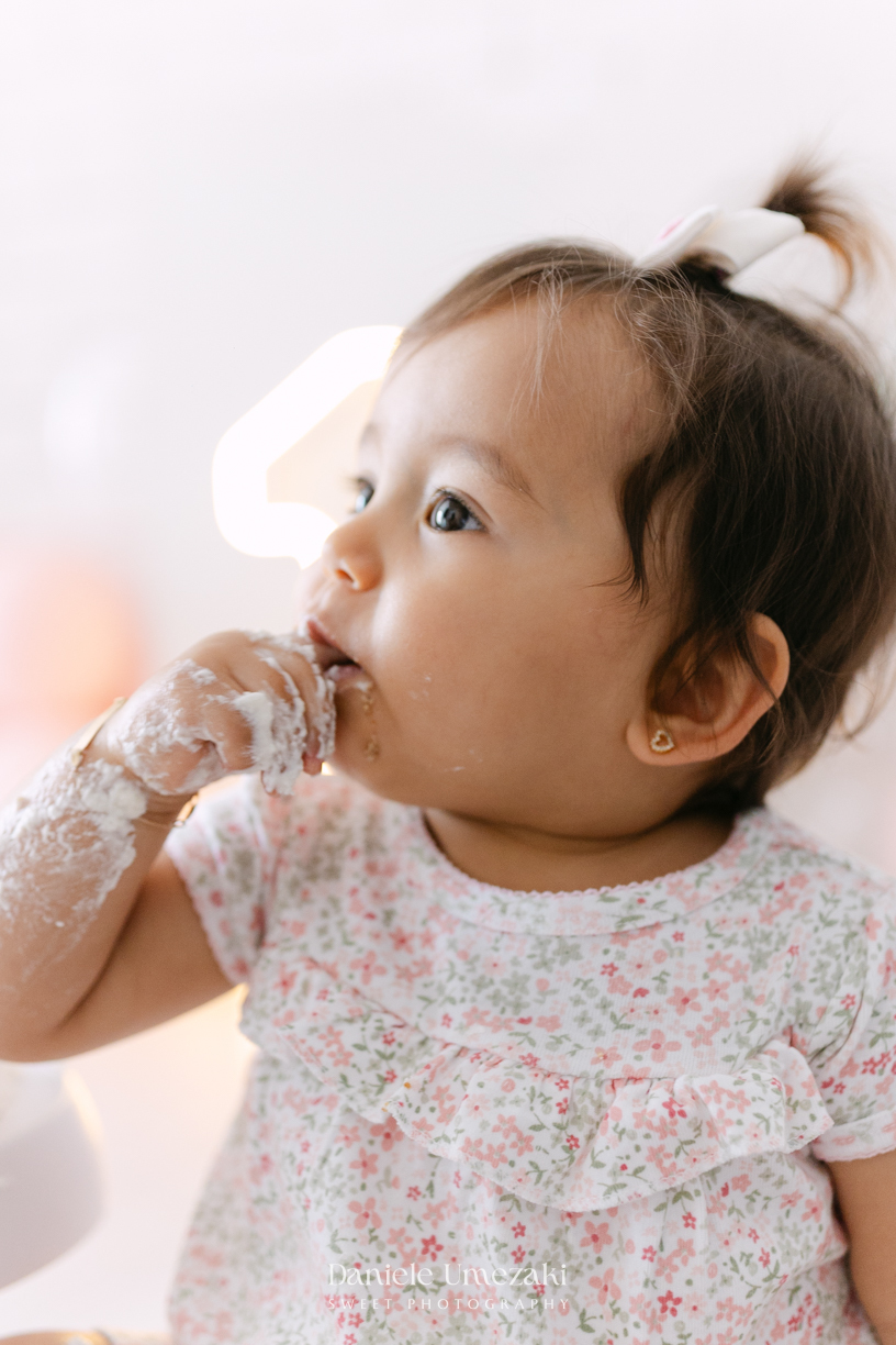 Smash the Cake da Luiza realizado em estúdio em Mogi das Cruzes, com bolo da Ume Doces. Ensaio fotográfico infantil registrando os primeiros momentos do aniversário de 1 ano com leveza, diversão e afeto.