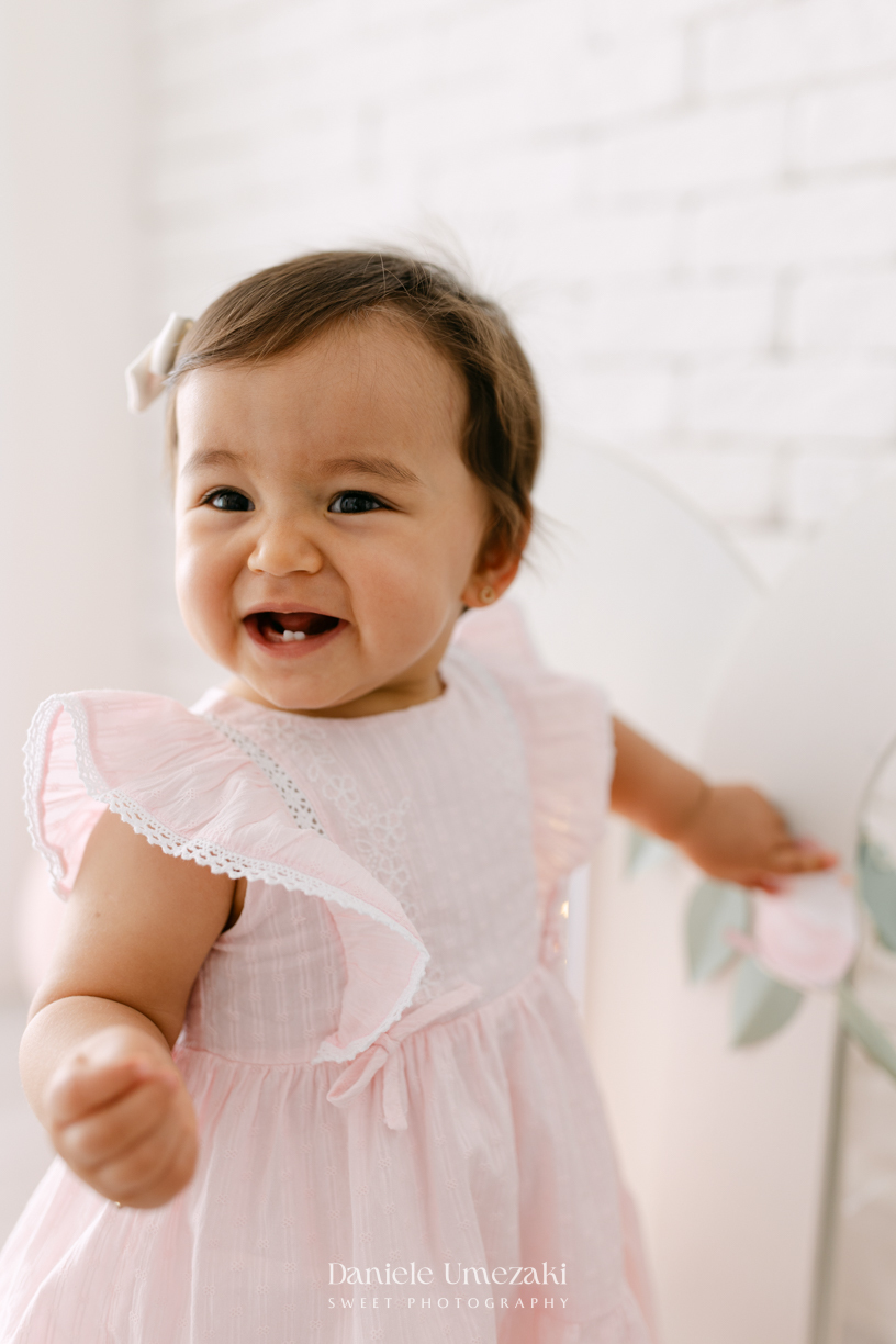 Smash the Cake da Luiza realizado em estúdio em Mogi das Cruzes, com bolo da Ume Doces. Ensaio fotográfico infantil registrando os primeiros momentos do aniversário de 1 ano com leveza, diversão e afeto.