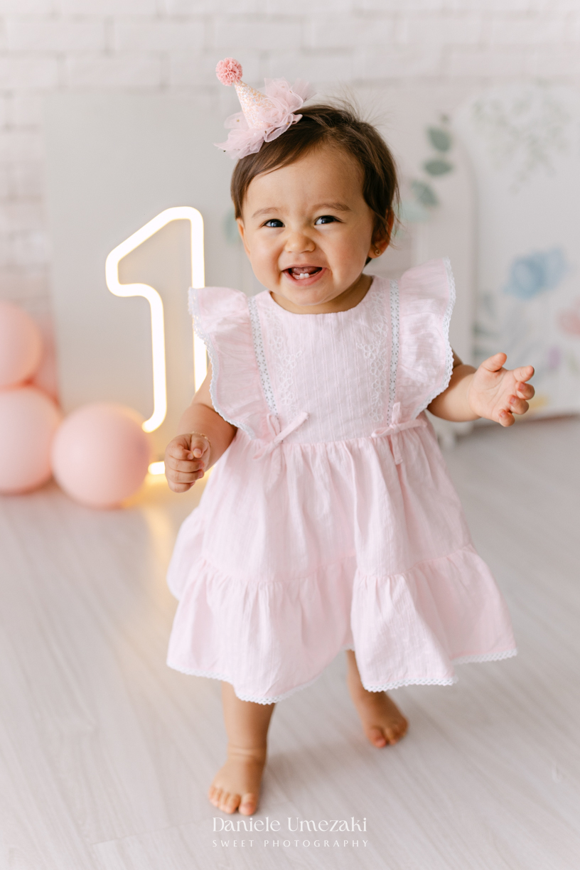 Smash the Cake da Luiza realizado em estúdio em Mogi das Cruzes, com bolo da Ume Doces. Ensaio fotográfico infantil registrando os primeiros momentos do aniversário de 1 ano com leveza, diversão e afeto.