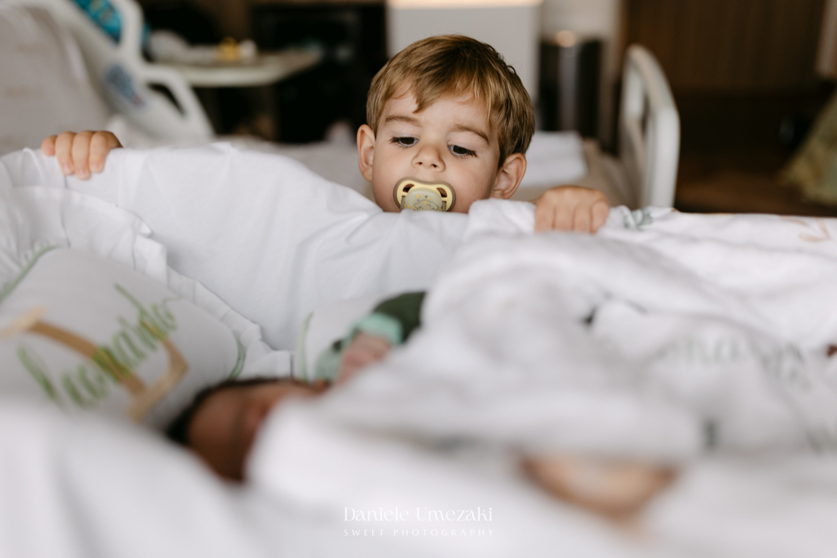 Encontro de irmãos na Maternidade São Luiz Star em São Paulo, registrando o momento em que Bernardo conhece o pequeno Leonardo pela primeira vez, fotografado por Dani Umezaki