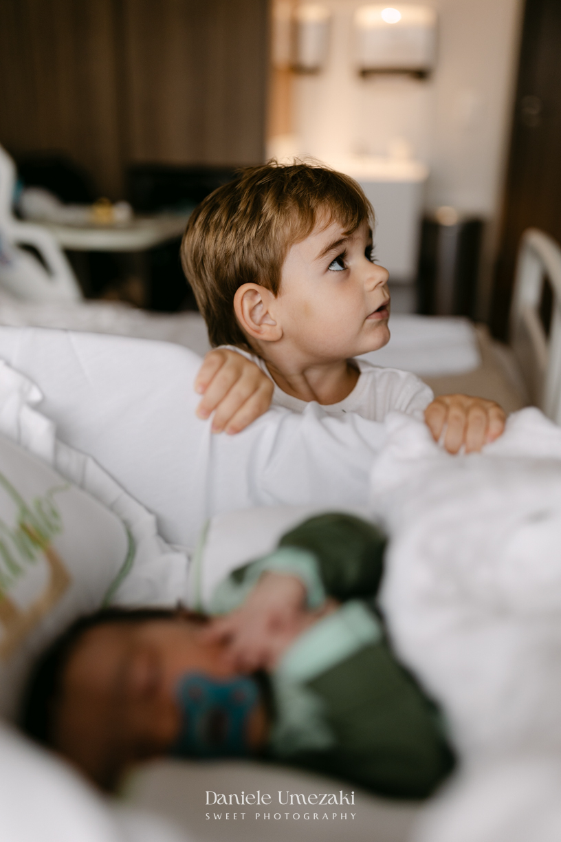 Encontro de irmãos na Maternidade São Luiz Star em São Paulo, registrando o momento em que Bernardo conhece o pequeno Leonardo pela primeira vez, fotografado por Dani Umezaki