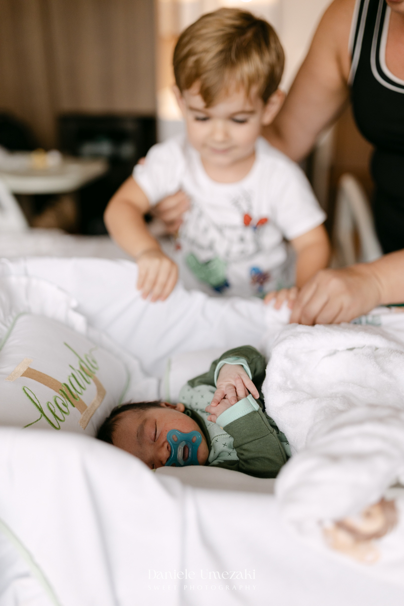 Encontro de irmãos na Maternidade São Luiz Star em São Paulo, registrando o momento em que Bernardo conhece o pequeno Leonardo pela primeira vez, fotografado por Dani Umezaki