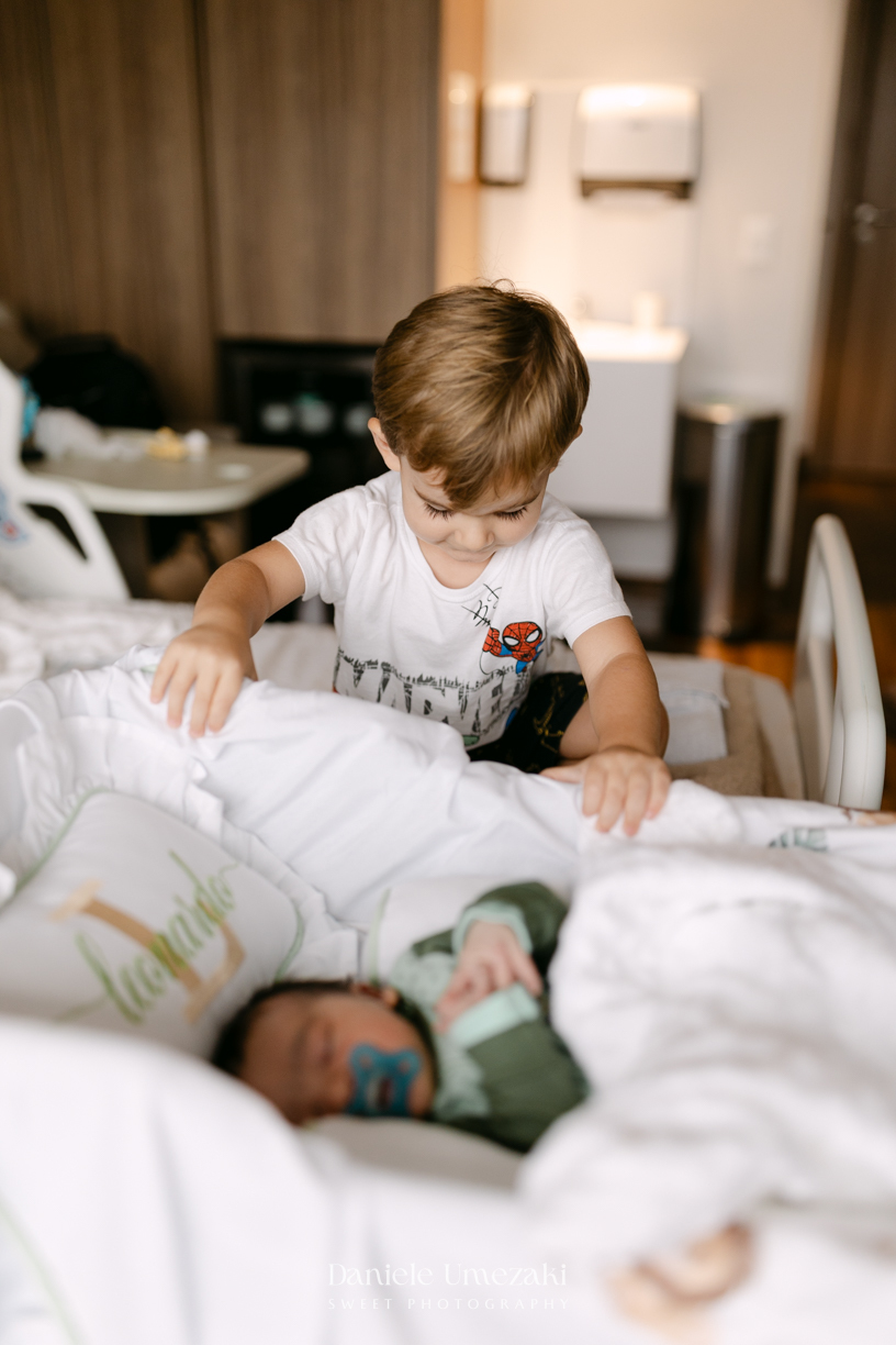 Encontro de irmãos na Maternidade São Luiz Star em São Paulo, registrando o momento em que Bernardo conhece o pequeno Leonardo pela primeira vez, fotografado por Dani Umezaki