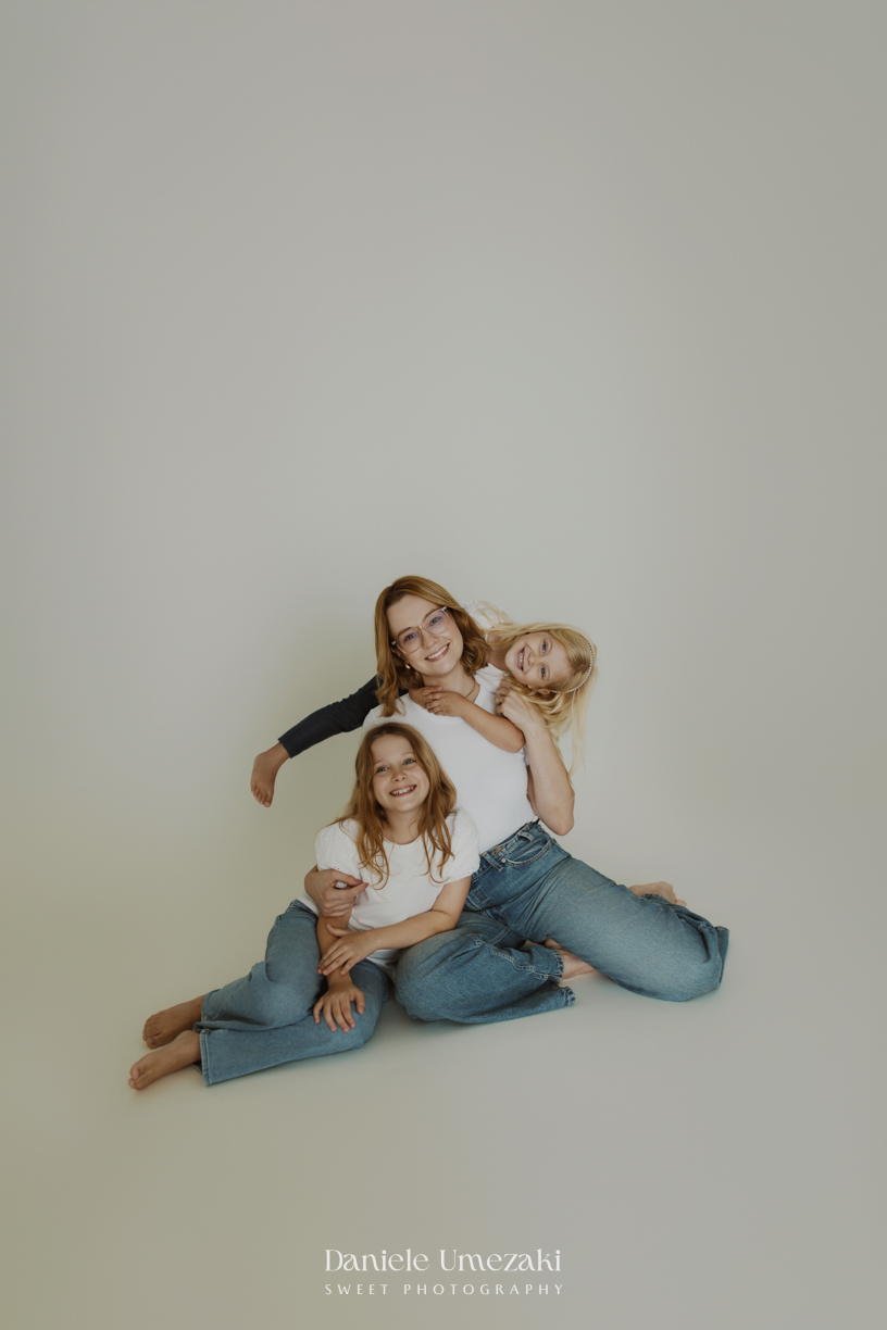 Ensaio de família em estúdio em Mogi das Cruzes com Kamilla e suas duas filhas, registrando a conexão, os abraços e a beleza da infância de forma leve, natural e atemporal por Dani Umezaki.