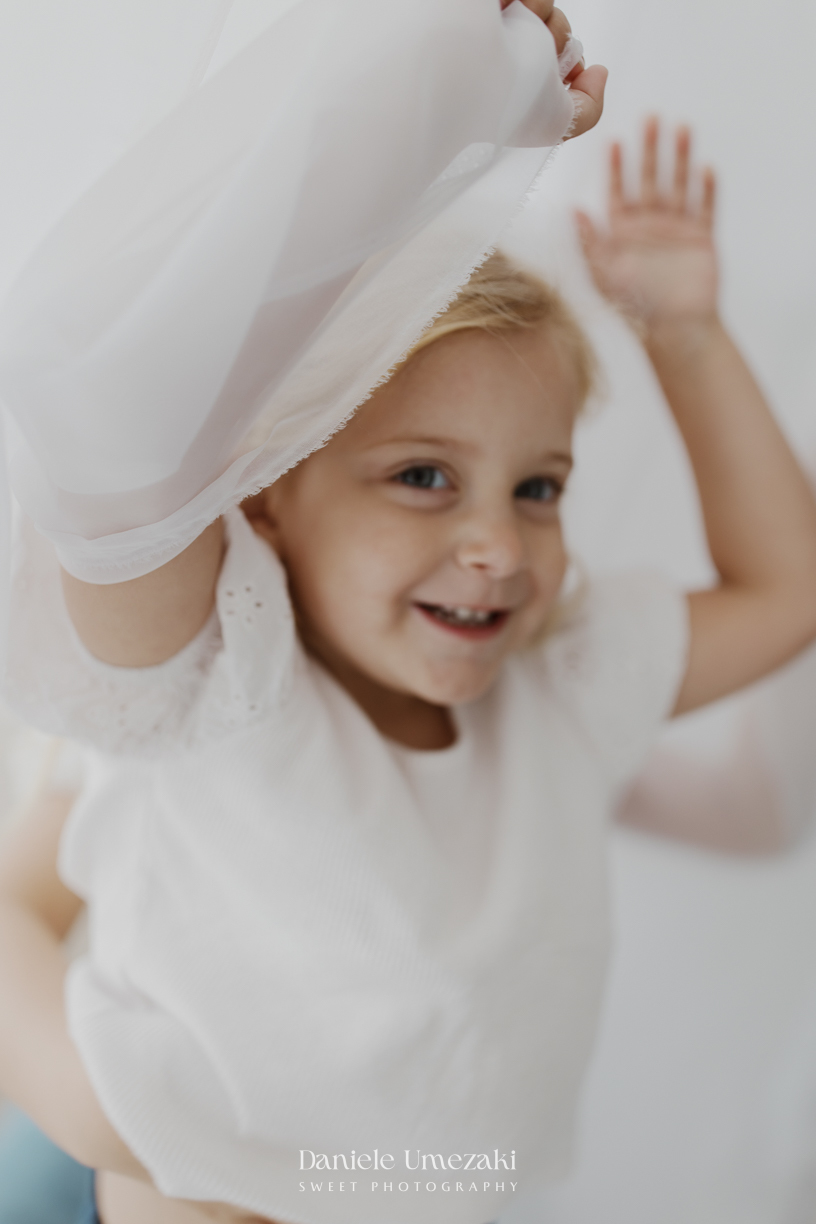 Ensaio de família em estúdio em Mogi das Cruzes com Kamilla e suas duas filhas, registrando a conexão, os abraços e a beleza da infância de forma leve, natural e atemporal por Dani Umezaki.