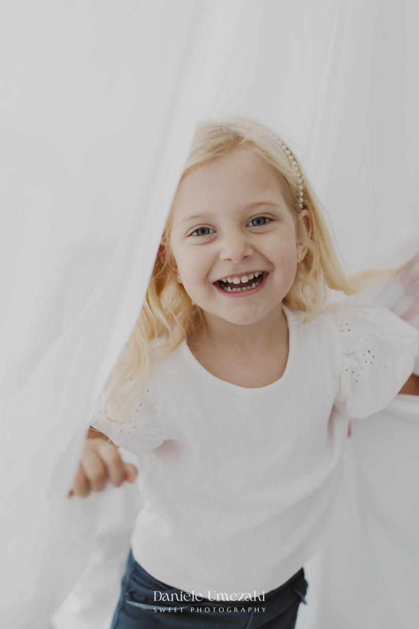 Ensaio de família em estúdio em Mogi das Cruzes com Kamilla e suas duas filhas, registrando a conexão, os abraços e a beleza da infância de forma leve, natural e atemporal por Dani Umezaki.