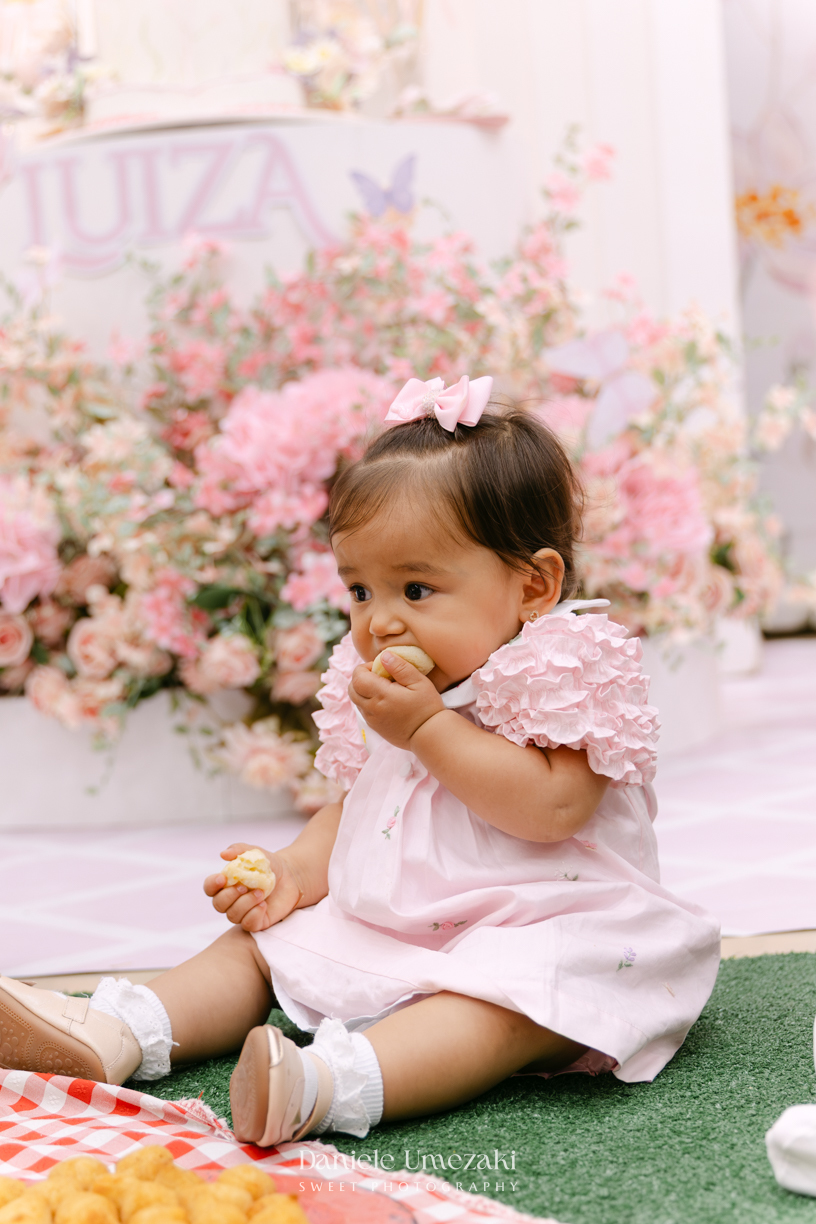 Aniversário de 1 ano da Luiza realizado no Buffet Santa Arruaça em Mogi das Cruzes, com decoração Jardim da Luiza assinada pela Doce de Laço e registrado por Dani Umezaki