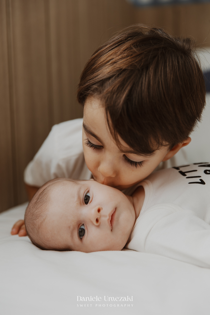 Família reunida durante ensaio lifestyle em casa em Arujá com o bebê Enrico de 2 meses, registrado por Dani Umezaki com fotografia leve, natural e atemporal