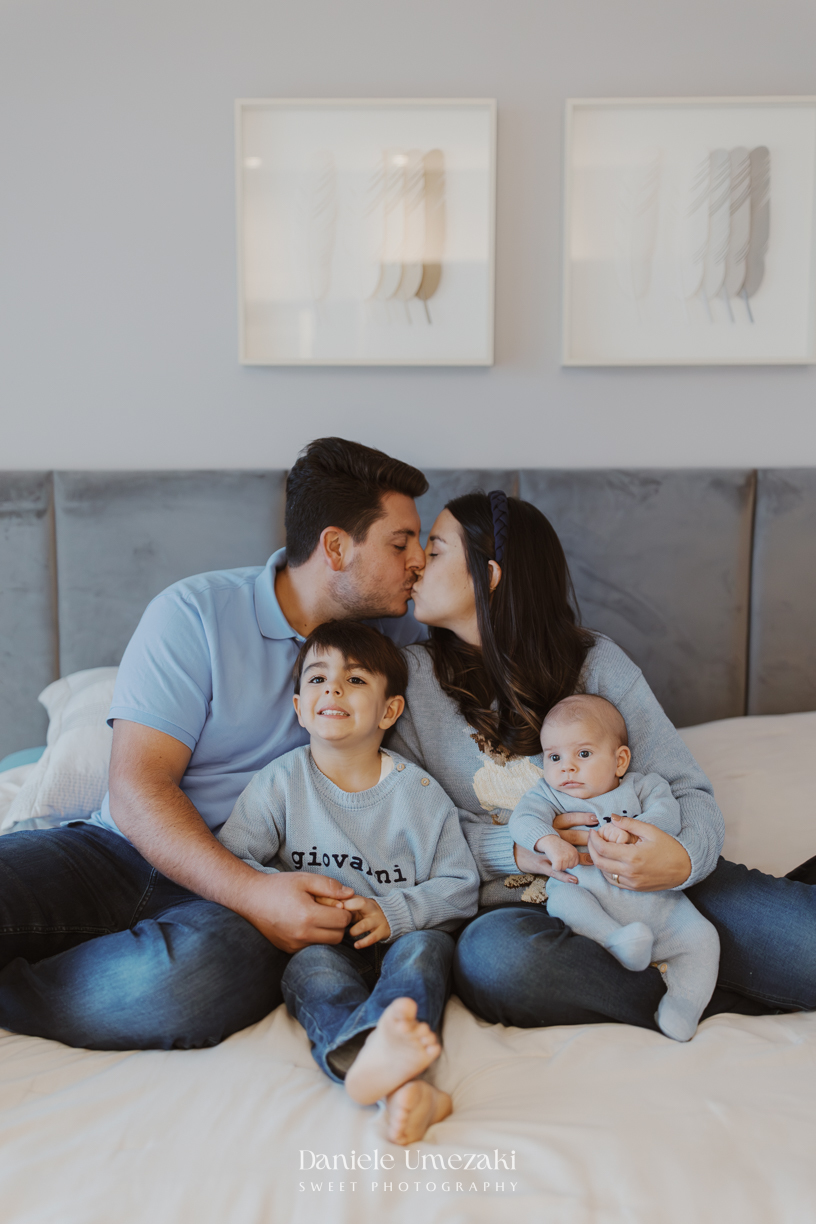 Família reunida durante ensaio lifestyle em casa em Arujá com o bebê Enrico de 2 meses, registrado por Dani Umezaki com fotografia leve, natural e atemporal