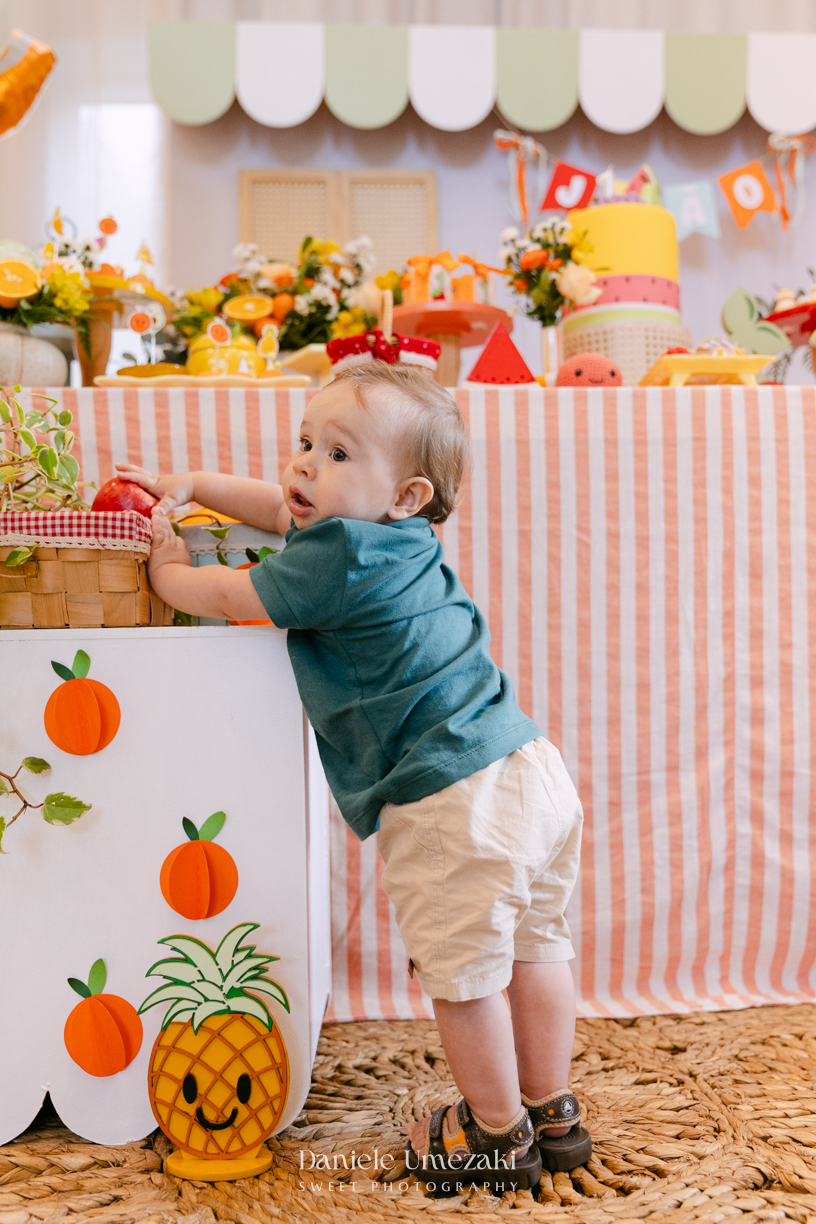 João comemorando seu aniversário de 1 ano com tema de frutas em festa realizada no salão do condomínio, com decoração da Cerejeira Decora e fotografia de Dani Umezaki.