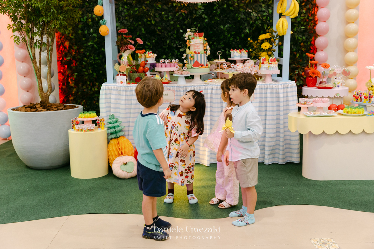 Maya sorrindo em frente à decoração de feira criada pela Panda Pink durante seu aniversário de 4 anos no Buffet Santa Arruaça, em Arujá.