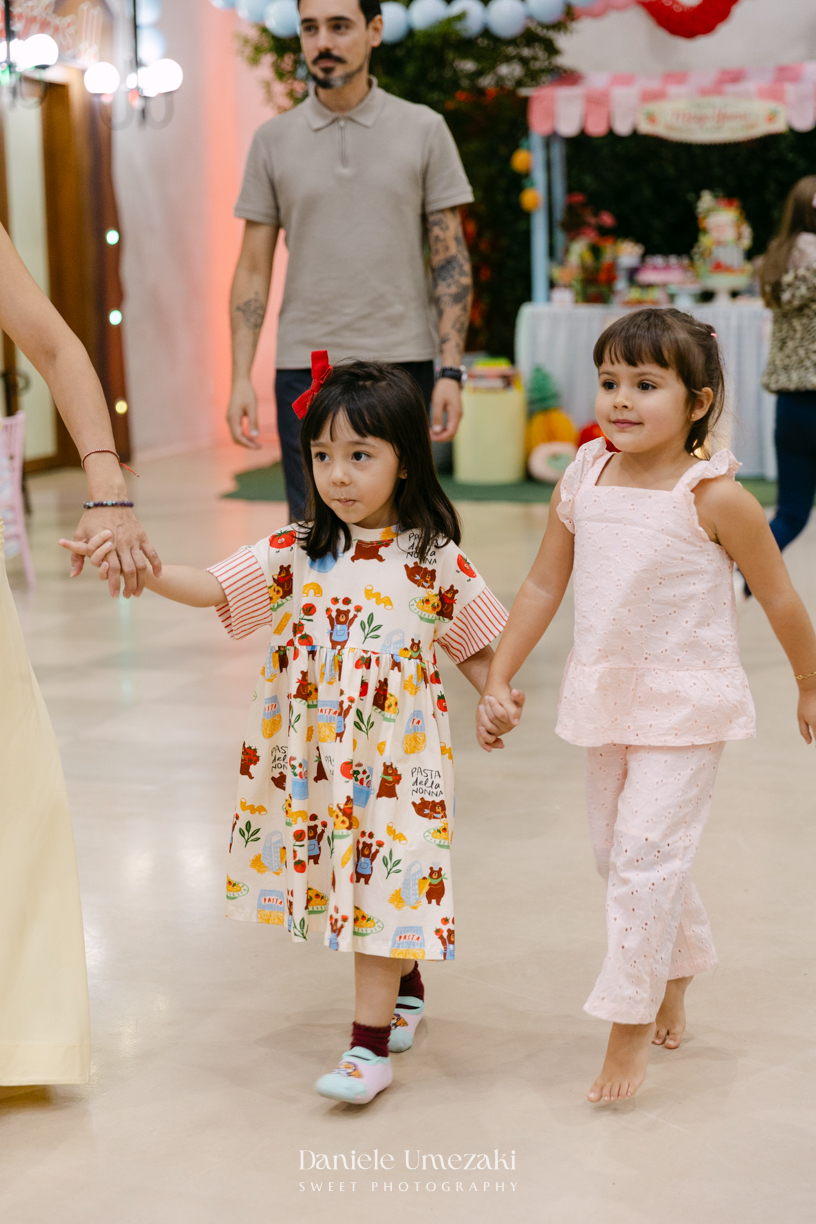 Maya sorrindo em frente à decoração de feira criada pela Panda Pink durante seu aniversário de 4 anos no Buffet Santa Arruaça, em Arujá.
