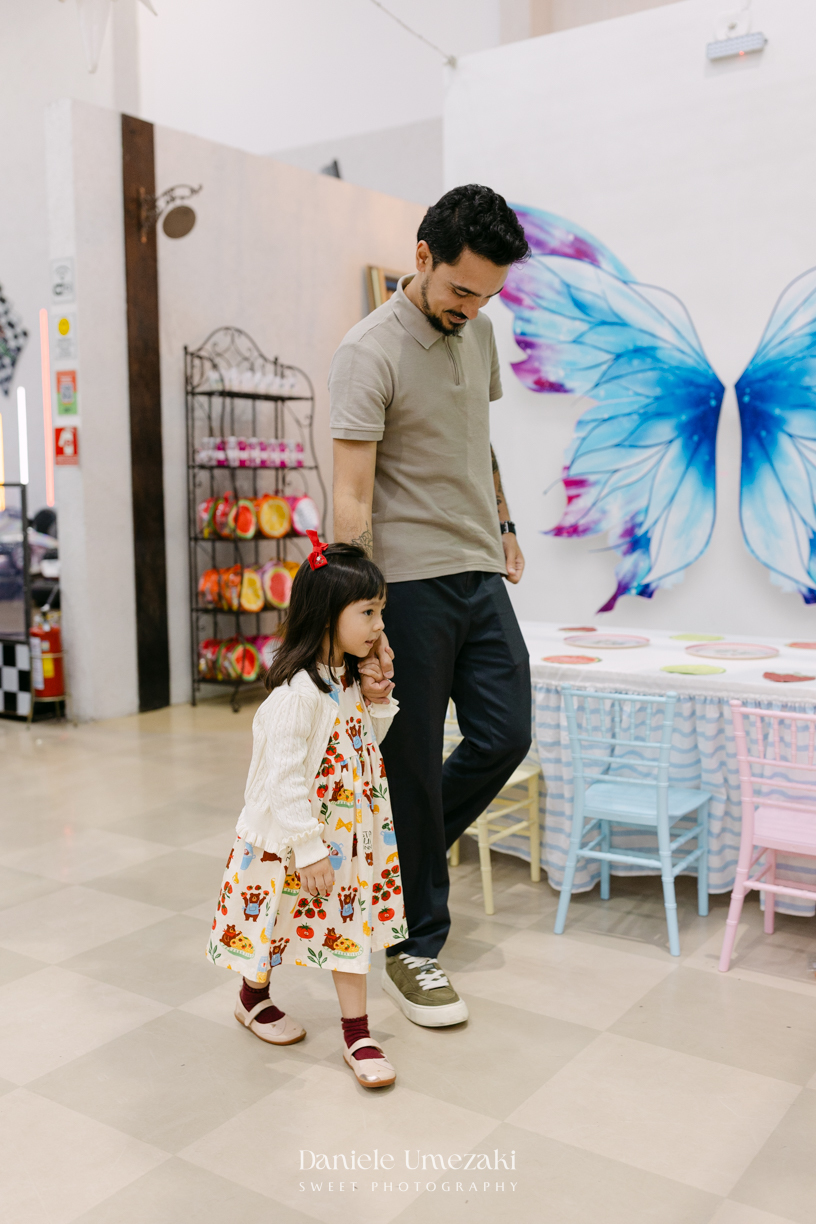 Maya sorrindo em frente à decoração de feira criada pela Panda Pink durante seu aniversário de 4 anos no Buffet Santa Arruaça, em Arujá.